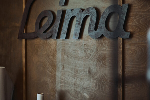 Tatuointiliike Leiman puinen takaseinä johon kiinnitetty petsattu Leima-logo.
