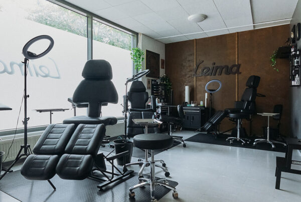 Tatuointiliike Leiman sisätilat. Kuvassa on tatuointipenkkejä ja välineitä. Taustaseinällä Leiman logo.