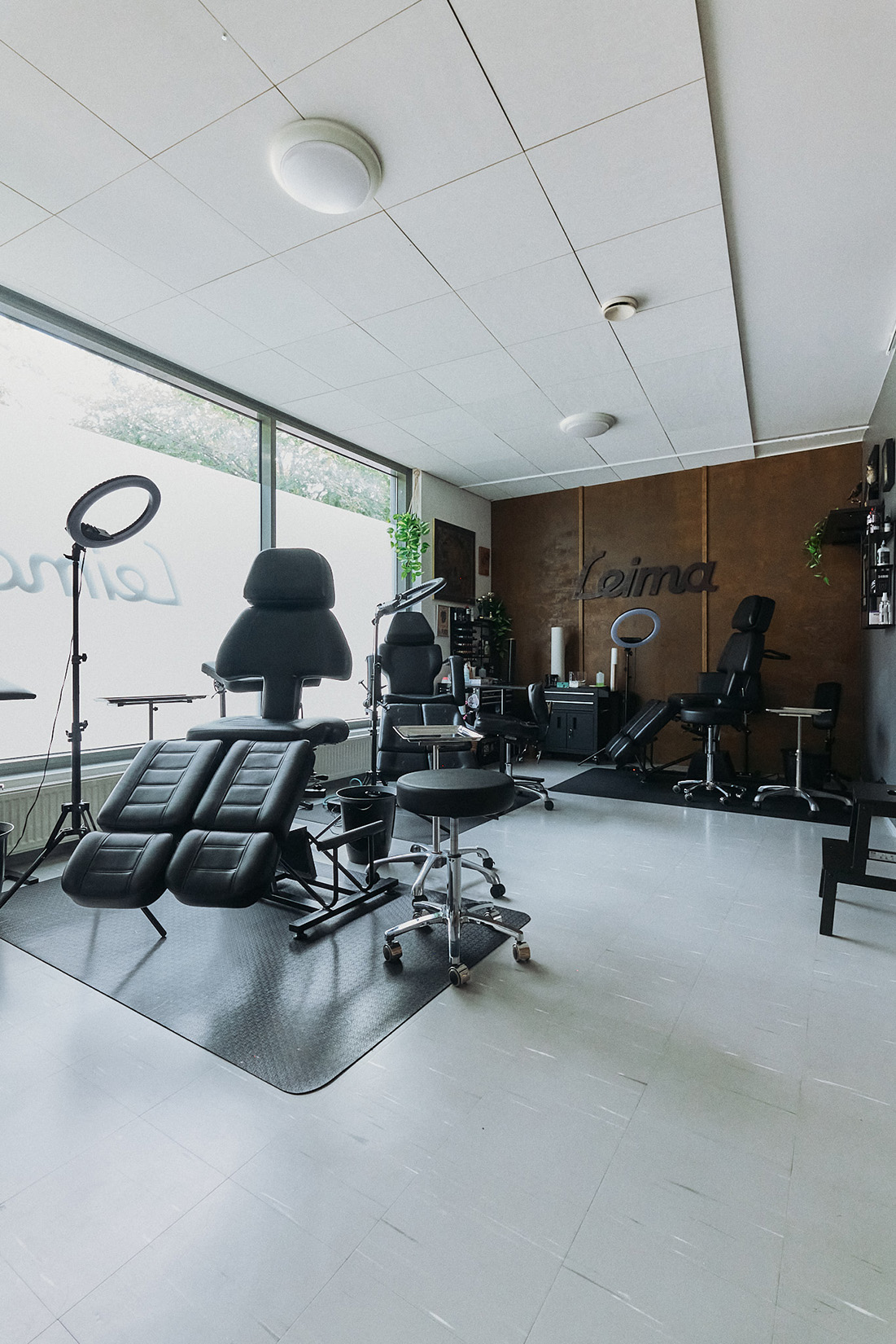 Tatuointiliike Leiman sisätilat. Kuvassa on tatuointipenkkejä ja välineitä. Taustaseinällä Leiman logo.