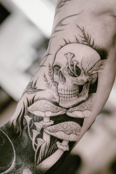 Dogma Noirin tekemä tatuointi jossa kallo ja sieniä.