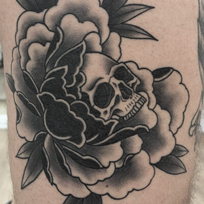 Tatuoija Bryan Scottin tekemä pioni-pääkallotatuointi jalassa. Tyyli on Old School. Tatuointi on tehty tatuointiliike Leimassa.
