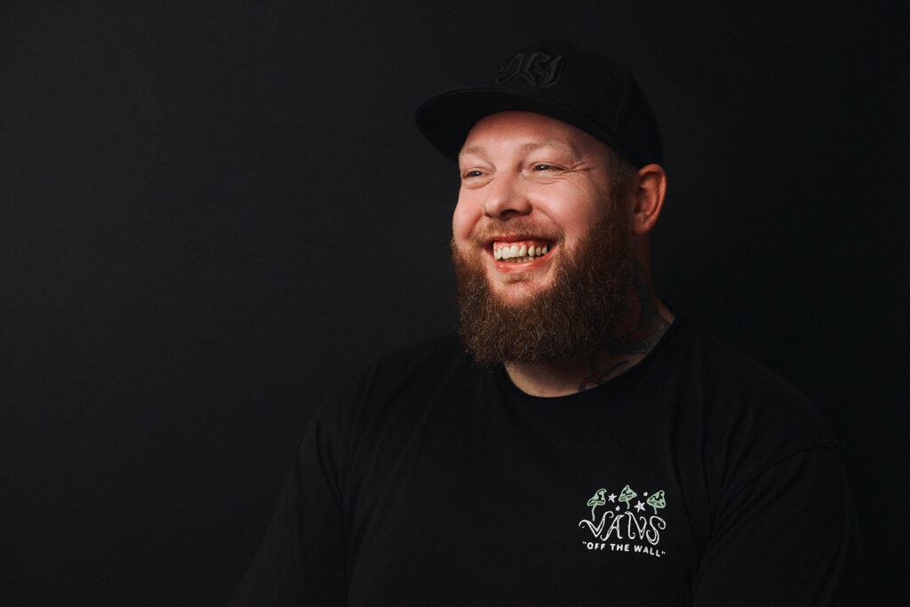 Tatuointiliike Leiman tatuoija Bryan Scott henkilökuvassa mustaa taustaa vasten.