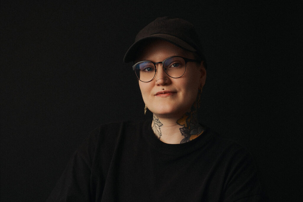 Tatuointiliike Leiman tatuoija Jole henkilökuvassa mustaa taustaa vasten.